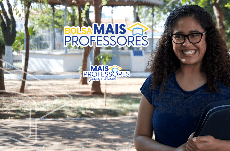 Mulher jovem sorridente com óculos segurando materiais em ambiente escolar ao ar livre.