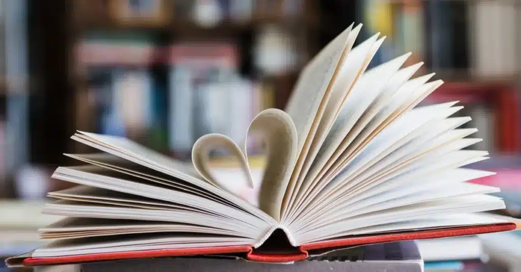 Inspire-se para Ler Mais em 2025 Páginas de um livro aberto com as pontas viradas para formar um coração, simbolizando o amor pela leitura e o poder dos livros em transformar hábitos de vida.