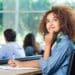 Jovem estudante universitária pensativa e inspirada em sala de aula, refletindo sobre carreira e o futuro do mercado de trabalho com esses cursos em alta.