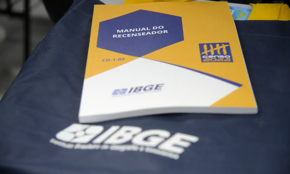 Manual do Recenseador IBGE Censo 2022 Manual do Recenseador do IBGE para o Censo 2022 sobre tecido azul com logo do IBGE