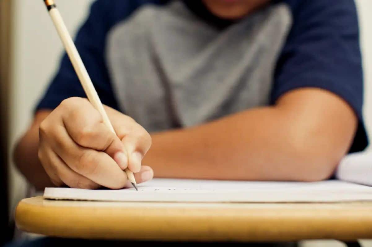 Estudante escrevendo em um caderno durante uma aula de qualificação técnica.