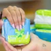 Mãos segurando um pacote de absorventes femininos azul com verde, embalagem com 8 unidades