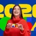 Mulher jovem sorrindo, vestindo suéter vermelho, segurando cartão do programa Família 2026 com fundo colorido e texto grande