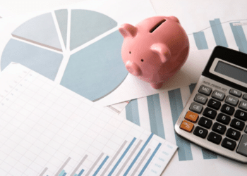 Cofrinho de porco, gráficos de crescimento e calculadora sobre a mesa, representando o planejamento estratégico para alcançar a independência financeira.