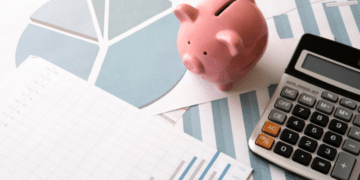 Cofrinho de porco, gráficos de crescimento e calculadora sobre a mesa, representando o planejamento estratégico para alcançar a independência financeira.