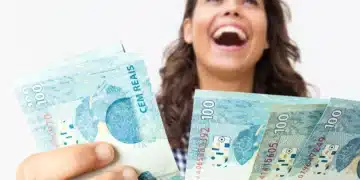 Mulher alegre segurando várias notas de cem reais em fundo branco