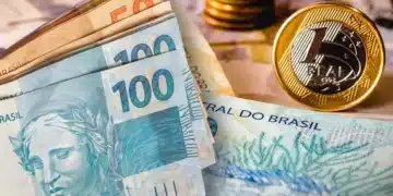 Cédulas de real brasileiro nas denominações de 50 e 100 reais com moedas de 1 real ao fundo