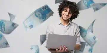 Homem sorridente segurando laptop enquanto cédulas de dinheiro voam ao redor em fundo neutro