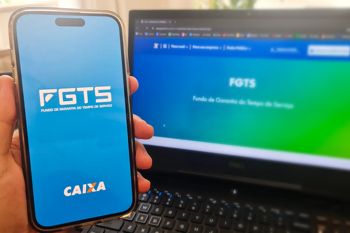 Aplicativo FGTS da Caixa com Fundo de Garantia Mão segurando celular com tela do aplicativo FGTS Caixa, fundo azul e texto branco