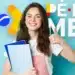 Jovem mulher sorridente de camiseta branca segurando cadernos e fazendo sinal positivo
