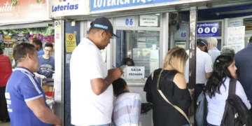 Pessoas esperando em fila na lotérica Fique Rico, com caixa fechado e ambiente movimentado.