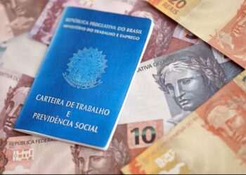 Carteira de trabalho brasileira e notas de dinheiro, representando o impacto do novo salário mínimo e seguro-desemprego em 2026.