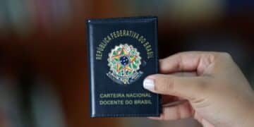 Carteira Nacional Docente do Brasil sendo exibida em primeiro plano por uma pessoa