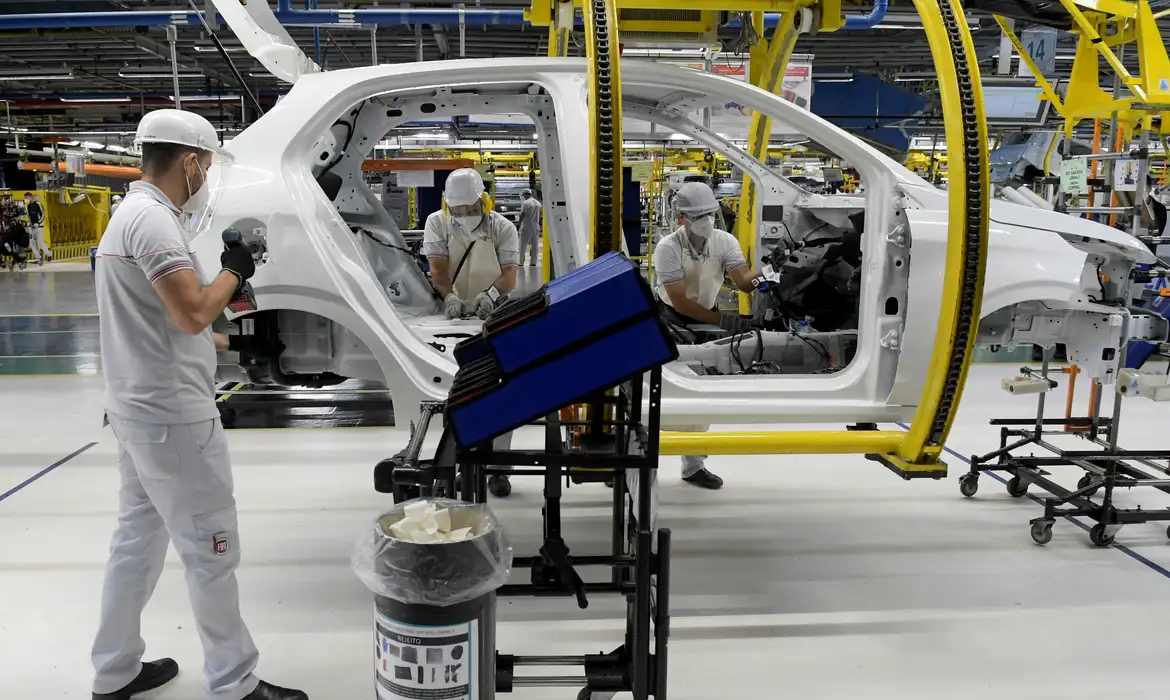 Operários em atividade na indústria automotiva “Trabalhadores em linha de montagem automotiva realizando produção de veículos.