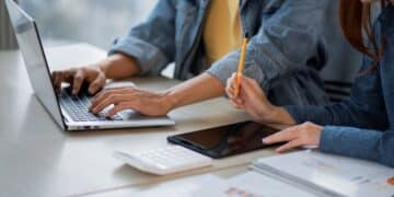 Pessoa utilizando um laptop com gráficos e ícones que representam Inteligência Artificial (IA), Podcast e Conteúdo Digital. A imagem simboliza a formação profissional online e 100% gratuita oferecida pelo Governo.