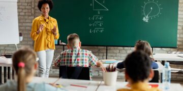 Professora de matemática explicando conteúdos para alunos, representando o compromisso com a educação.
