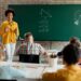 Professora de matemática explicando conteúdos para alunos, representando o compromisso com a educação.