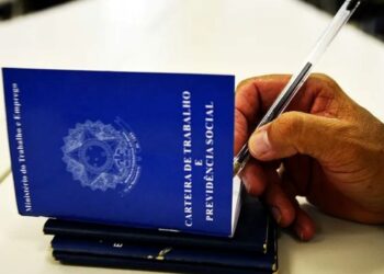 Carteira de Trabalho sendo preenchida por trabalhador segurando caneta