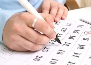 Calendário sendo marcado à mão, representando o último dia útil do ano e dúvidas sobre expediente e feriado.