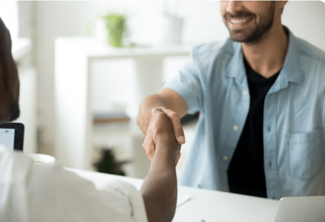 Duas pessoas apertando as mãos em ambiente de trabalho com expressões amigáveis