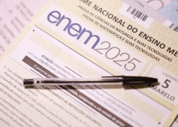 Caderno de prova Enem 2025 amarelo com caneta esferográfica sobre folha de rascunho