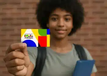 Adolescente segura cartão colorido do Programa Bolsa Família