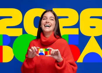Mulher sorrindo e segurando o cartão do Bolsa Família, com fundo colorido e o número 2026 destacado.