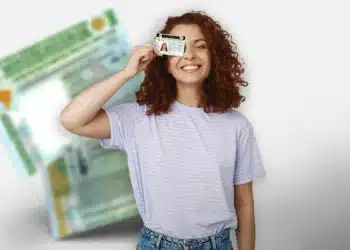 Mulher jovem com cabelo cacheado e camiseta listrada segurando carteira de motorista perto do rosto