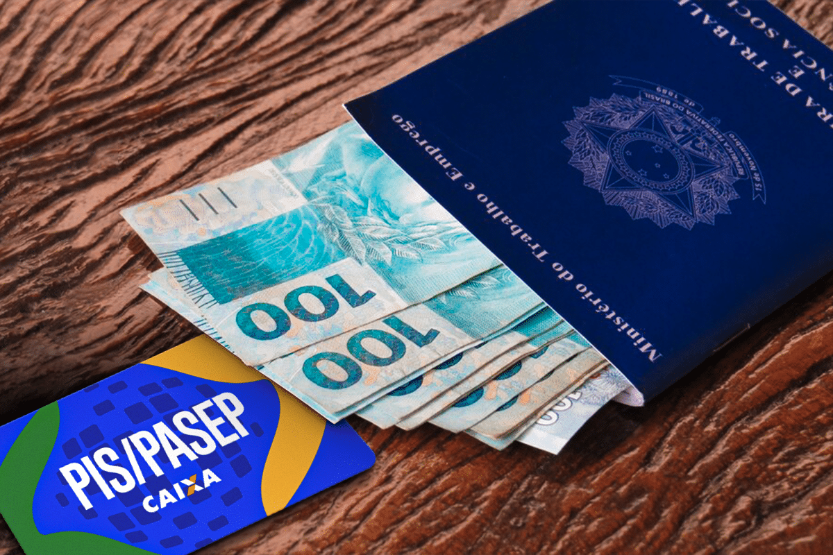 Carteira de trabalho azul com notas de cem reais e cartão PIS PASEP CAIXA sobre superfície de madeira