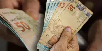 Notas de cinquenta reais sendo seguradas por mãos, simbolizando o aumento do salário mínimo no Brasil em 2026.