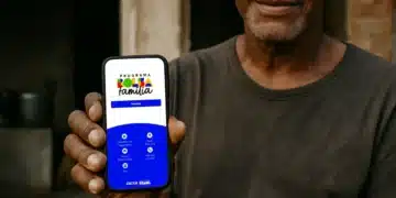 Homem segurando celular com aplicativo do Bolsa Família aberto em 2026