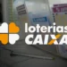 Logotipo das Loterias Caixa com bilhetes de sorteio ao fundo.