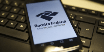 Smartphone exibindo o aplicativo da Receita Federal sobre teclado de computador