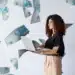 Mulher sorrindo com notebook rodeada de notas de cem reais, simbolizando ganhar dinheiro online em 2026