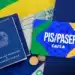 Imagem do abono salarial PIS/PASEP, mostrando a carteira de trabalho, cédulas de reais e o cartão do PIS emitido pela Caixa Econômica Federal, sobre um fundo com as cores da bandeira do Brasil