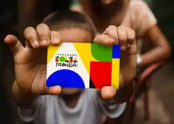 Criança segurando um cartão colorido do Programa Bolsa Família 2026