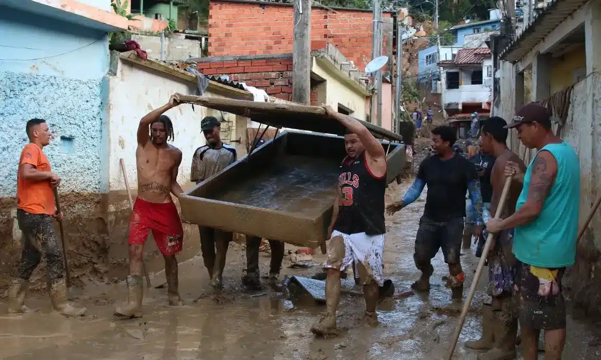 Recuperação de área atingida por desastre natural Trabalhadores ajudando na recuperação após desastre natural em uma cidade brasileira