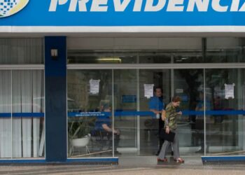 Entrada de agência do INSS com usuários durante período de suspensão temporária do atendimento presencial.