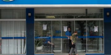 Entrada de agência do INSS com usuários durante período de suspensão temporária do atendimento presencial.