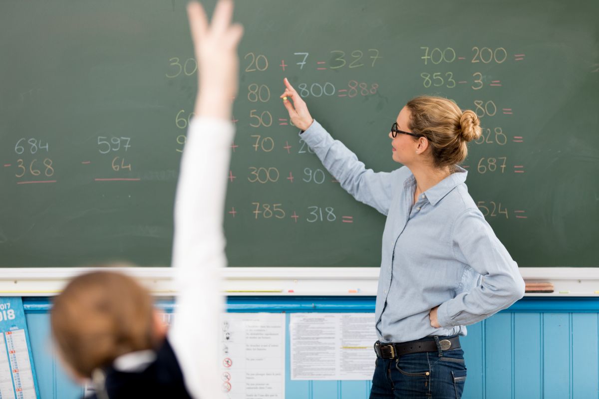 Professora explica conceitos matemáticos enquanto o quadro de aposentadoria dos professores é discutido em 2026, com novas regras sobre idade mínima e pontos