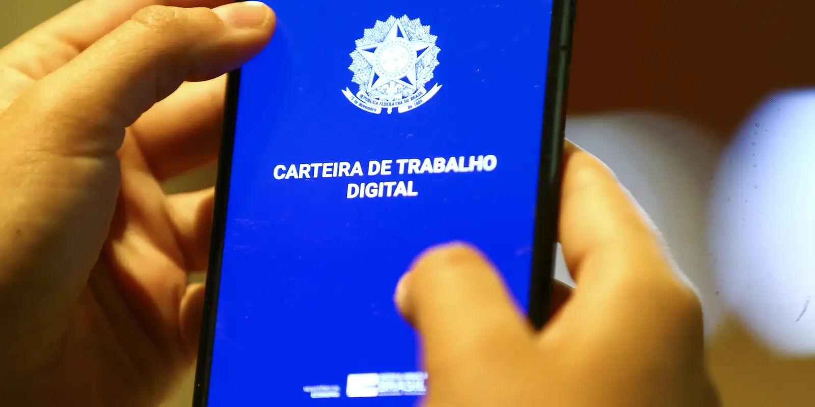 Acesse a sua carteira de trabalho digitalmente. Pessoa acessando a Carteira de Trabalho Digital no celular, destacando a digitalização dos registros profissionais.