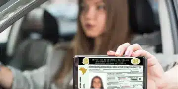 Mulher exibindo a versão digital da CNH no celular enquanto está dentro de um carro.