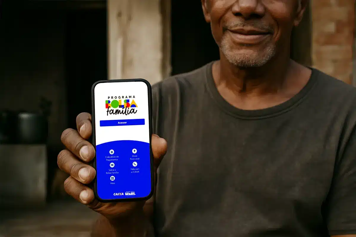 consulta situacao bolsa familia aplicativo celular Homem sorridente em primeiro plano segurando um smartphone que exibe a tela inicial azul e branca do aplicativo oficial do Programa Bolsa Família.