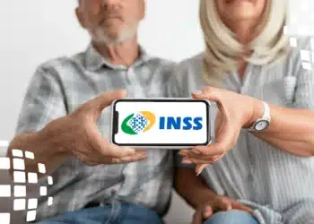 Casal de idosos segurando um smartphone com o logo do INSS na tela.