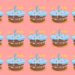 Desafio visual com uma ilustração de vários bolos de aniversário com cobertura azul, velas coloridas e estrelas, fundo rosa.