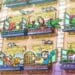 Desafio visual com uma fachada de prédio com várias janelas abertas, pessoas e animais interagindo nas varandas