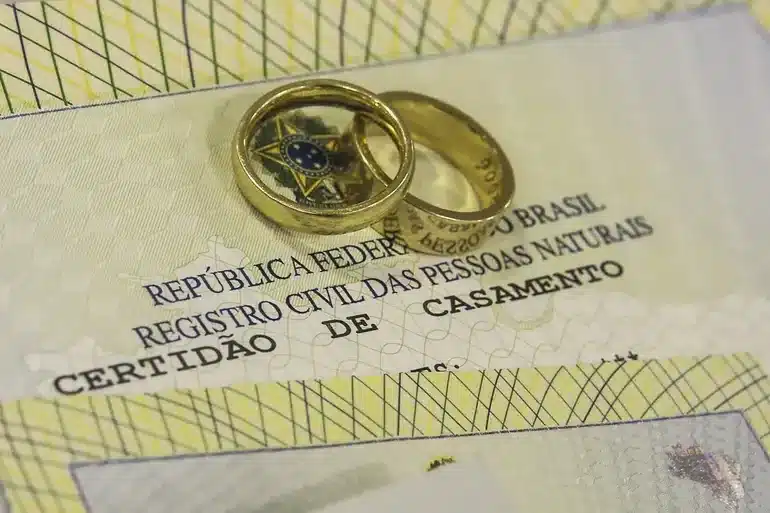 Certidão de casamento e anéis de casamento. Anéis de casamento sobre a certidão de casamento brasileira.