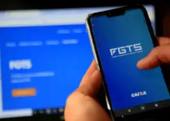 Pessoa acessando o aplicativo FGTS no celular com a interface da Caixa Econômica para verificar saldo e movimentações.
