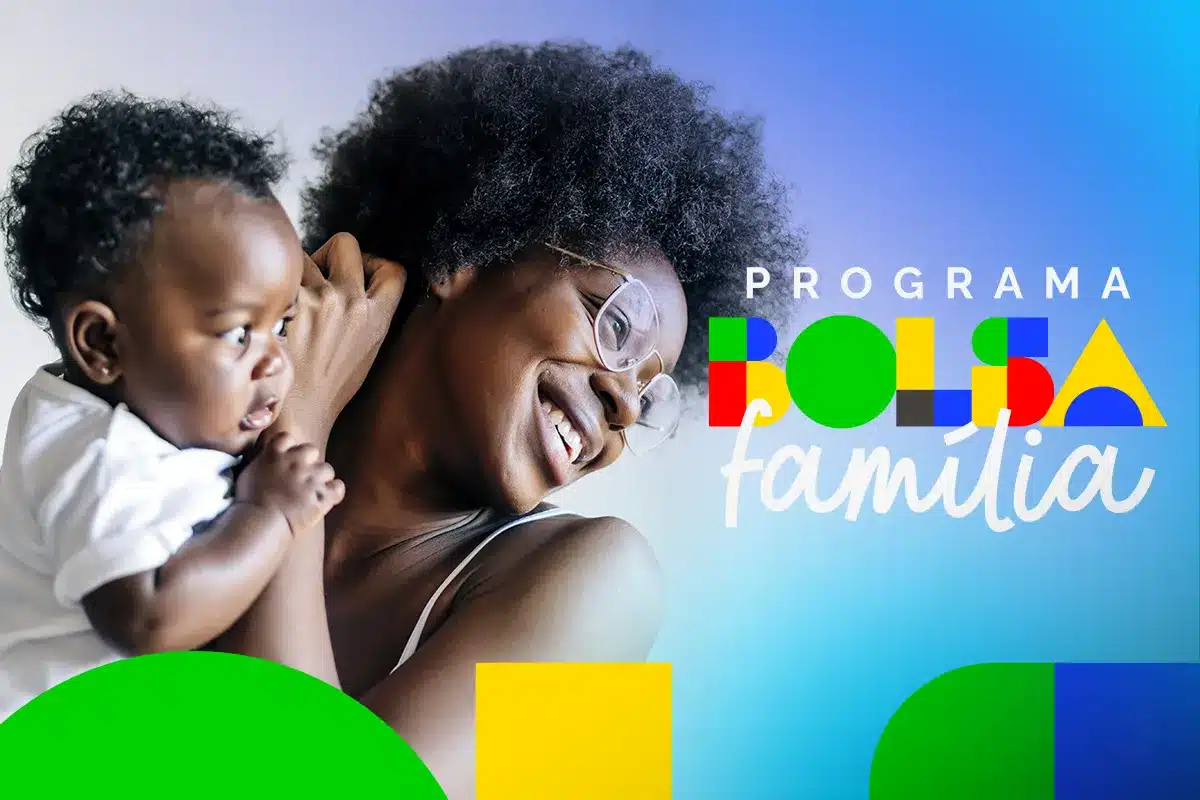 beneficios bolsa familia primeira infancia 2026 Mulher sorridente com óculos e cabelo crespo, segurando um bebê que olha para o lado, ambos em primeiro plano com o logotipo colorido "Programa Bolsa Família" ao fundo.