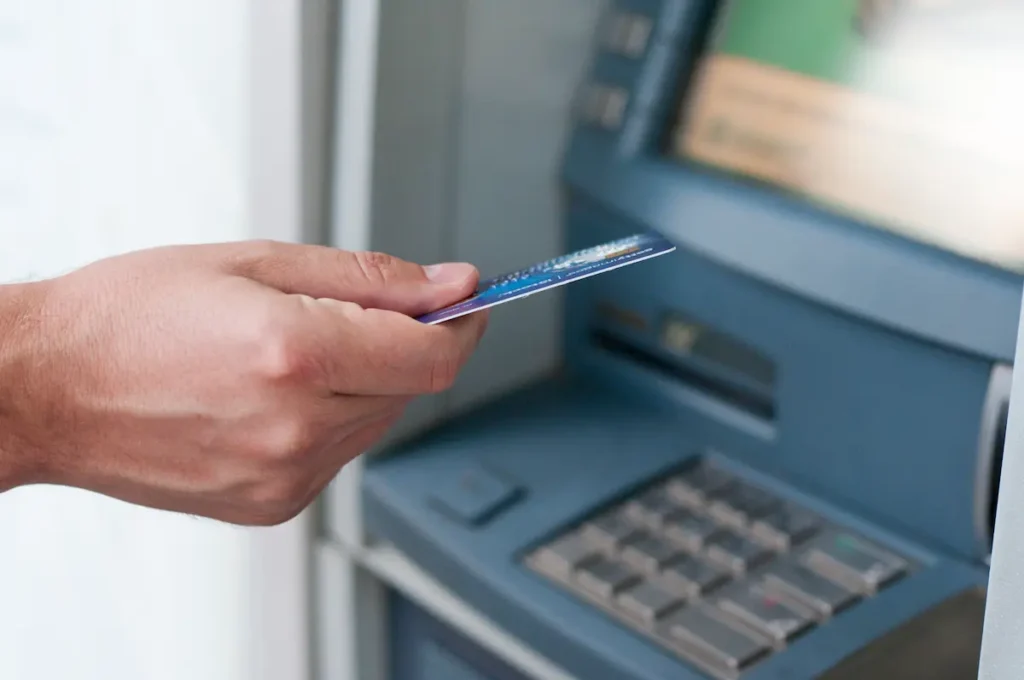 Inserção de Cartão no Caixa Eletrônico Homem inserindo cartão de crédito em caixa eletrônico para realizar transações bancárias.